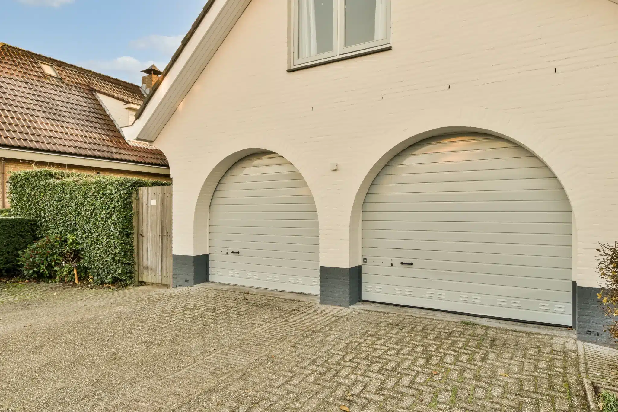 Double arched garage doors with white exterior and tiled roof, suitable for garage door opener installation.