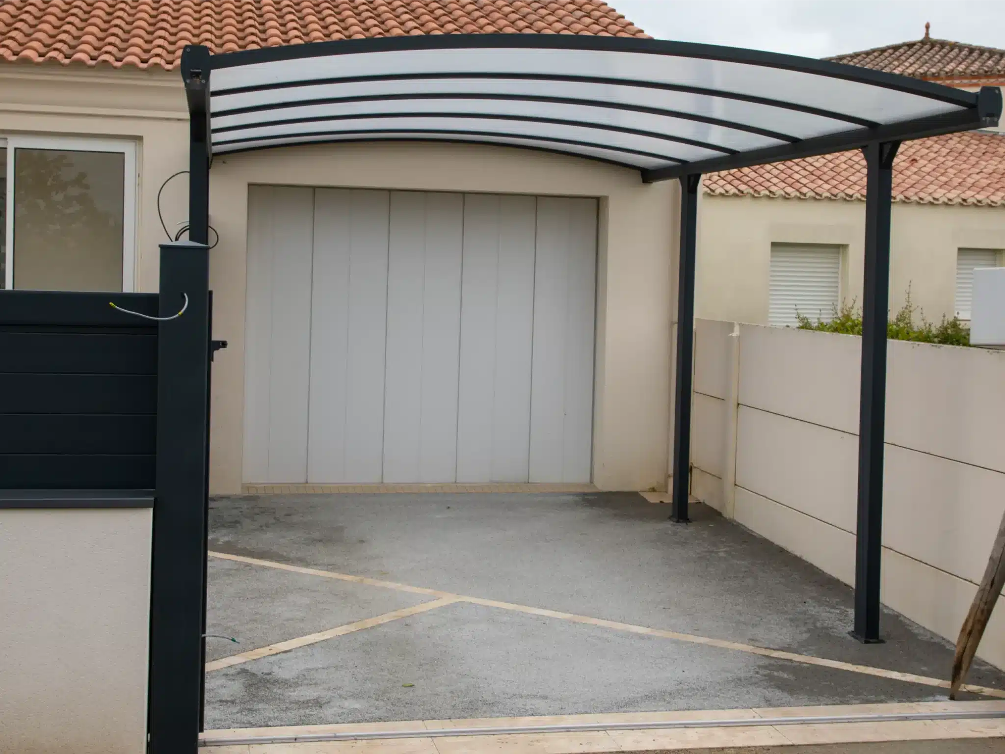 Light gray garage door beneath modern carport with curved roof, suitable for garage door opener installation.