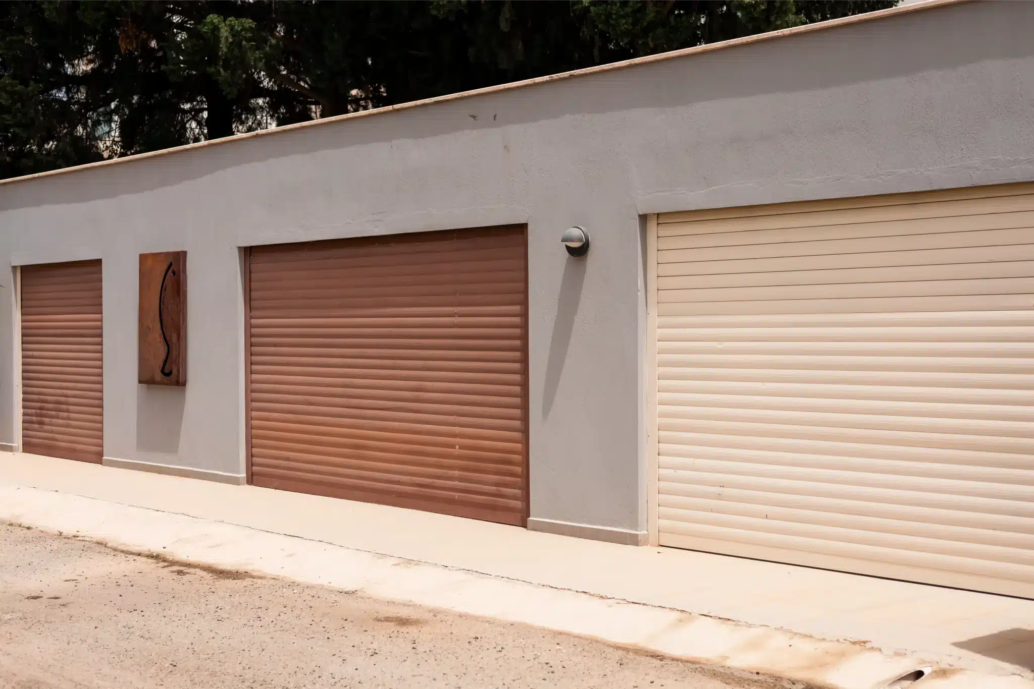 Row of brown and beige roller garage doors on a modern building, inspected for garage door spring repair services.