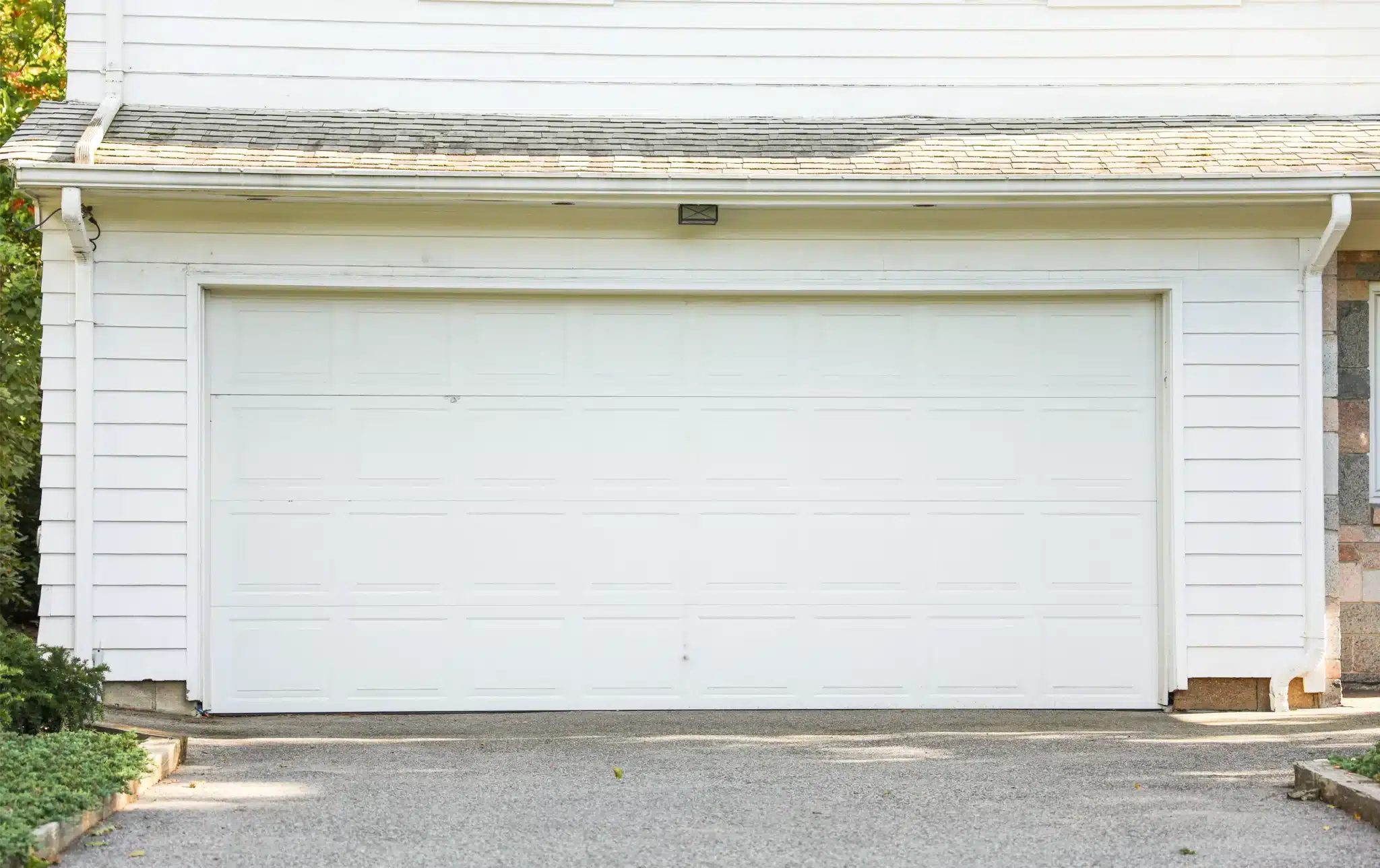 White double garage door with raised panels on a suburban house serviced for garage door spring repair.
