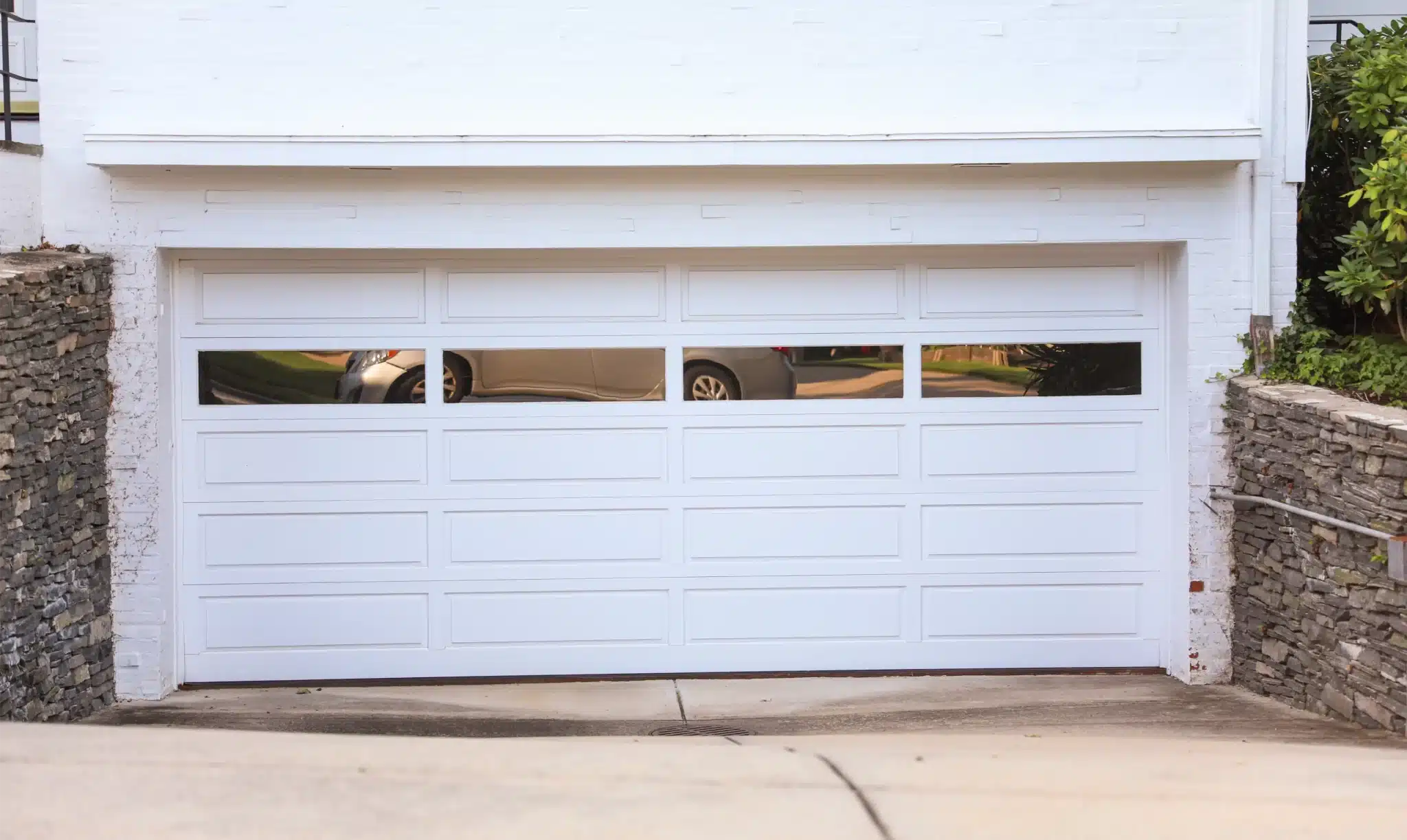 White garage door with glass windows on a brick driveway, maintained through garage door spring replacement services.
