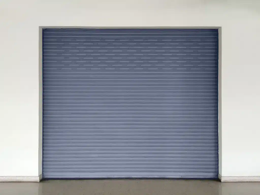 Closed gray roll-up garage door installed in a clean commercial or residential exterior wall